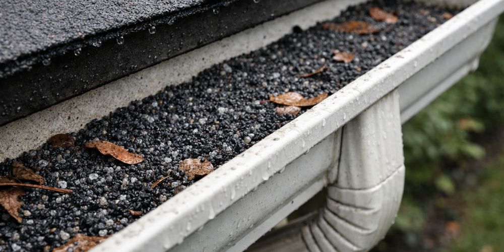 Granules from asphalt shingles collected in roof gutter after hailstorm damage